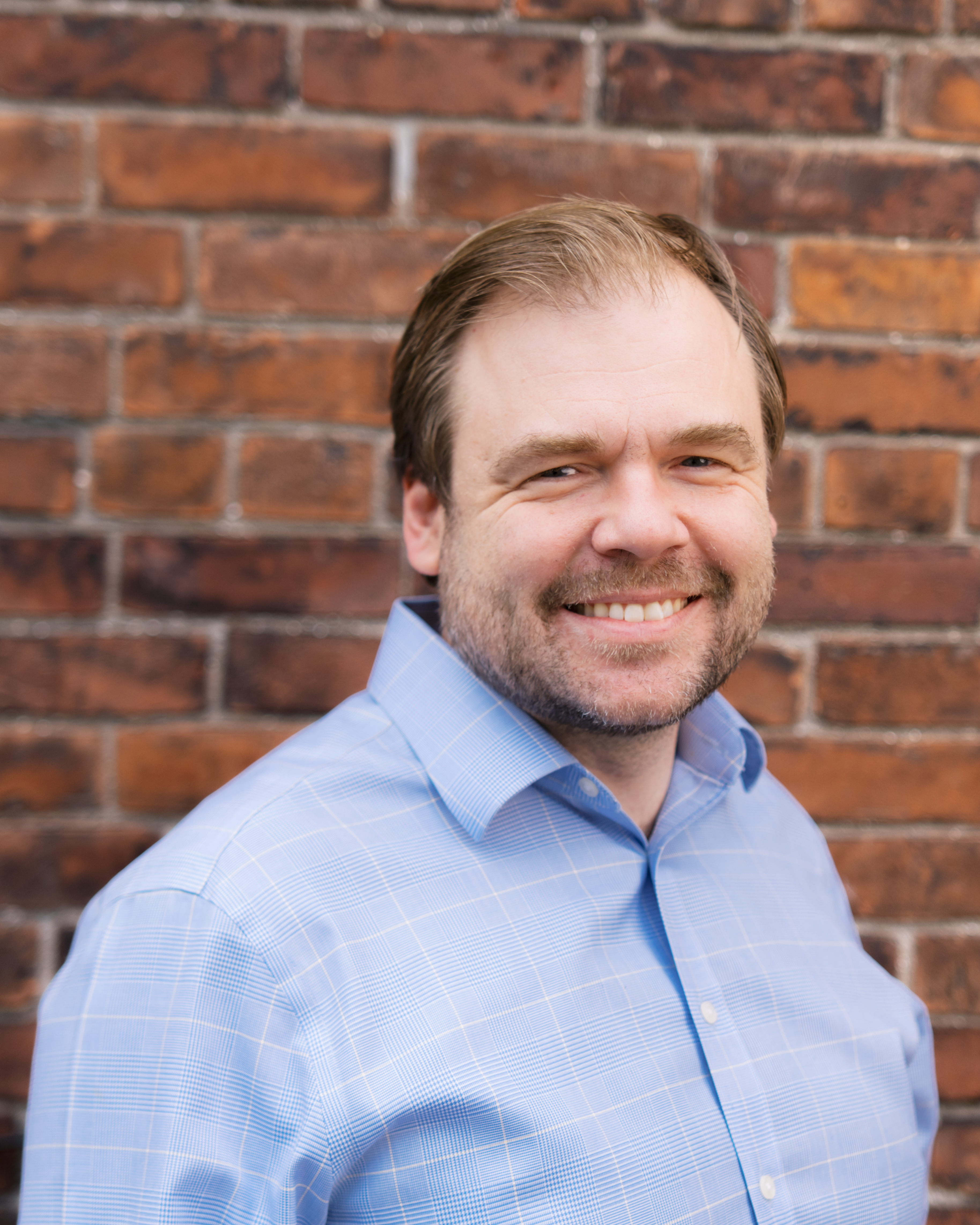 Headshot of Rob Luke in front of a brick wall.